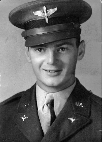 Black and white posed headshot of man wearing an Air Force uniform.  He is looking directly at the camera and smiling