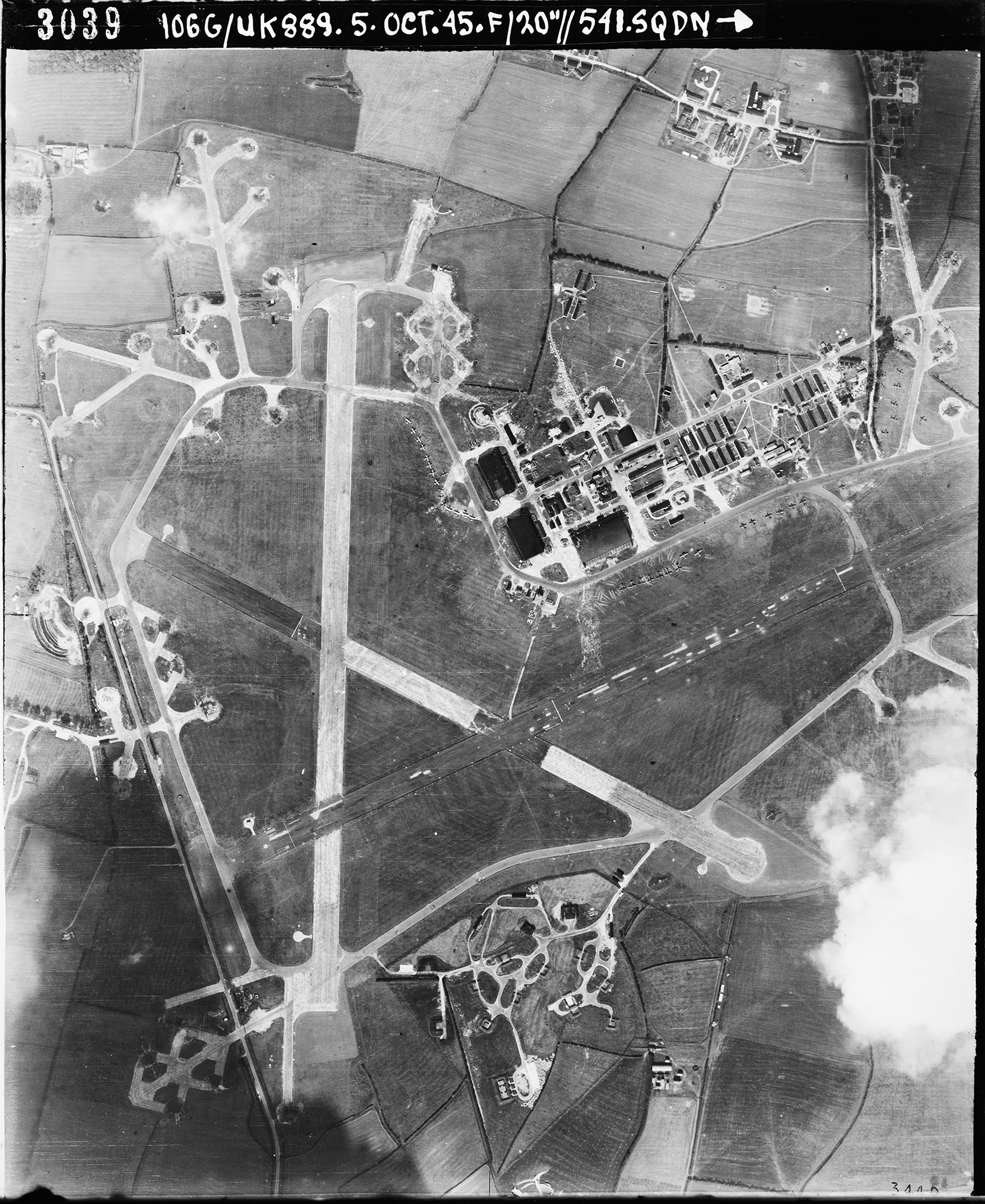 Aerial photograph of the west end of Molesworth airfield looking north, the control tower and two T2 hangars are right of the vertical runway, 5 October 1945. Photograph taken by No. 541 Squadron, sortie number RAF/106G/UK/889. English Heritage (RAF Photography).