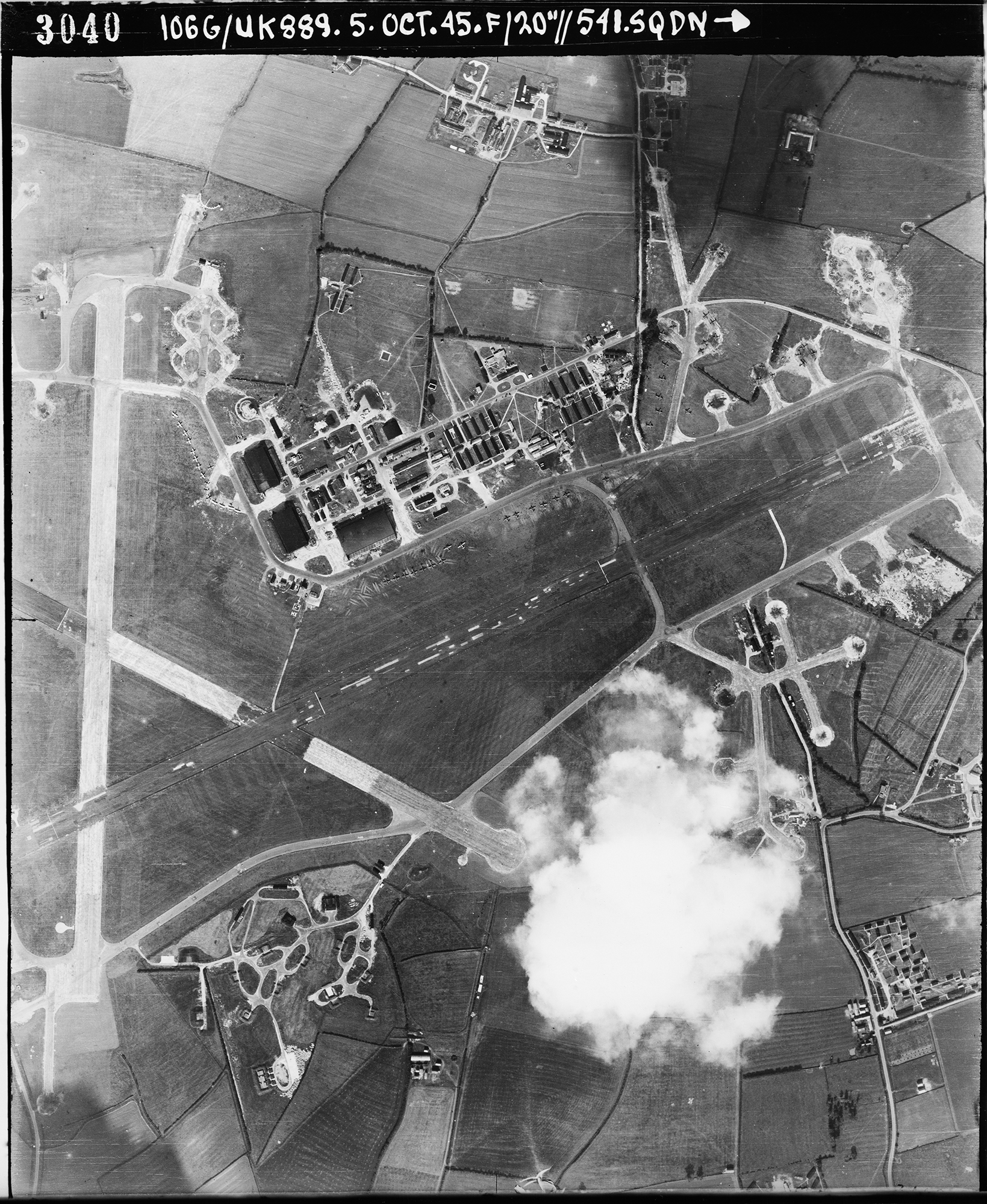 Aerial photograph of the east end of Molesworth airfield looking north, the control tower and two T2 hangars are right of the vertical runway, 5 October 1945. Photograph taken by No. 541 Squadron, sortie number RAF/106G/UK/889. English Heritage (RAF Photography).