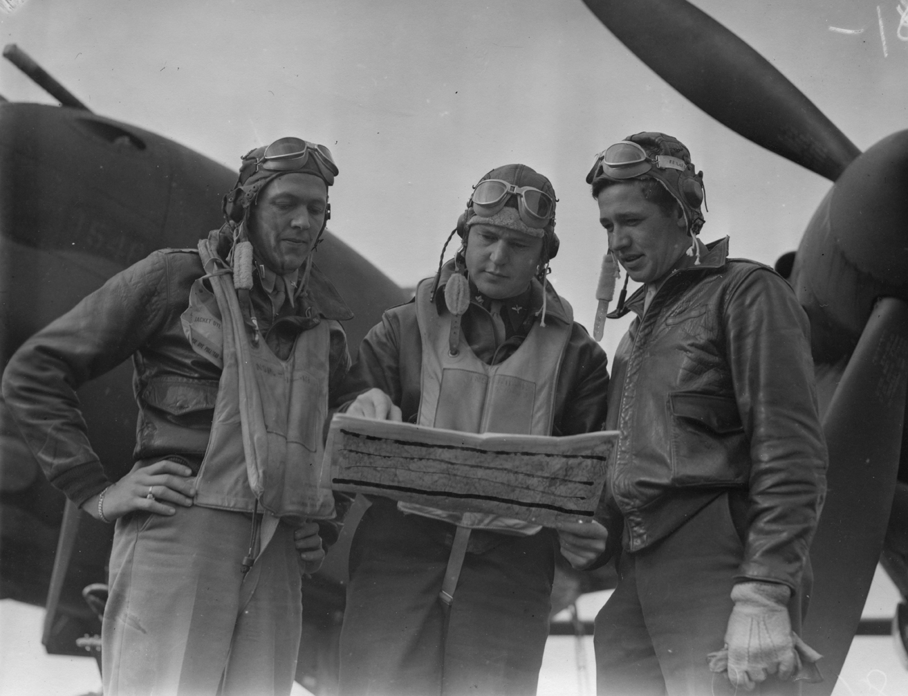 Pilots of the 79th Fighter Squadron, 20th Fighter Group, stand around a map at Kings Cliffe air base before mission over northern France, October 1943. L to R: First Lieutenant Merle B. Nichols, Seattle, Wash.; Major Nathaniel H. Blanton, Earlsboro, Oklahoma and First Lieutenant Richard P. Gatterdam, Columbus, Ohio. Censor has drawn lines across the map. Each of these pilots went on to command one of the squadrons of the 20th Fighter Group. Gatterdam commanded the 55th Fighter Squadron, Nichols the 77th a