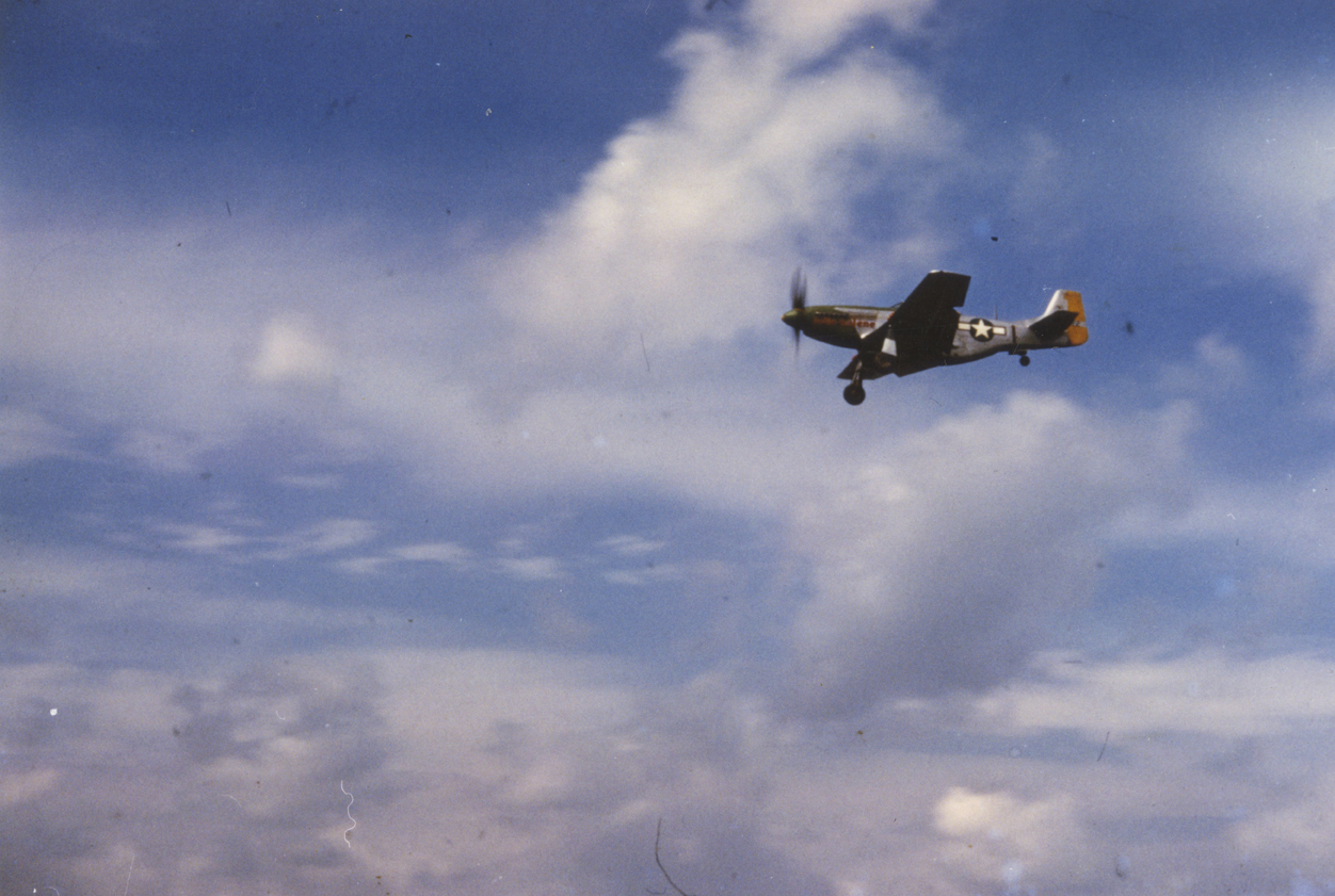 A P-51 Mustang (CV-I) of the 359th Fighter Group flies over East Wretham. Caption on reverse: '359th FG Photos Source: T.P. Smith via Char Baldridge, Historian Description: #45 368th FS P-51 in flight.'