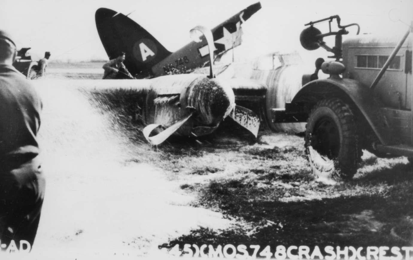 Ground crew of the 25th Bomb Group spray foam onto the crashed Mosquito (serial number NS748) at Watton, 19 April 1945. Official caption printed on image: '(G-AD-[illegible])(19-4-45)(MOS.748CRASH)(REST.)'