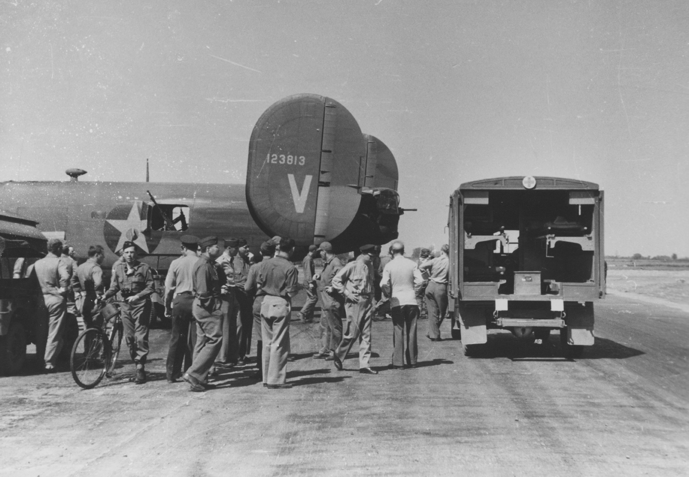 A medical truck and ground personnel of the 44th Bomb Group on standby as a B-24 Liberator (V, serial number 41-23813) nicknamed "Victory Ship" returns from a mission. Image via Colonel William R Cameron.