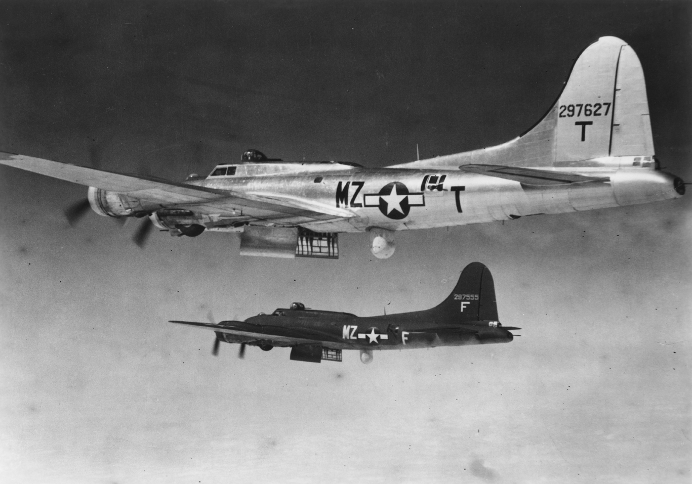 Two pathfinder B-17 Flying Fortresses, (MZ-F, serial number 42-97555) and (MZ-T, serial number 42-97627), of the 96th Bomb Group. Printed caption on reverse: '59089 A.C. PFF planes such as these flying high above German targets were able to see covered objectives thousands of feet below mirrored as small clusters of light in the screen of the Mickey instrument which they caried. The revolving micro-wave antenna which sends out and picks up impulses is housed in the covered "blister" in back of the bomb ba