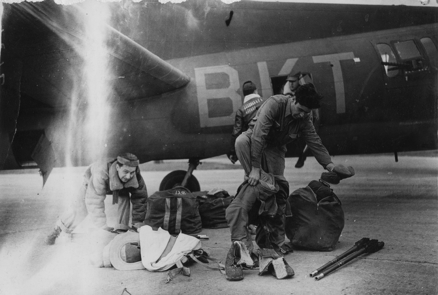 Personnel of the 384th Bomb Group don their flight gear before a mission to Berlin in their B-17 Flying Fortress. Image stamped on reverse: 'Passed for publication 24 Mar 1944.' [stamp] and '313403.' [Censor no.] A printed caption was previously attached to the reverse, however this has been removed. Handwritten caption on reverse: 'Berlin, 22/3/44, 231740.'