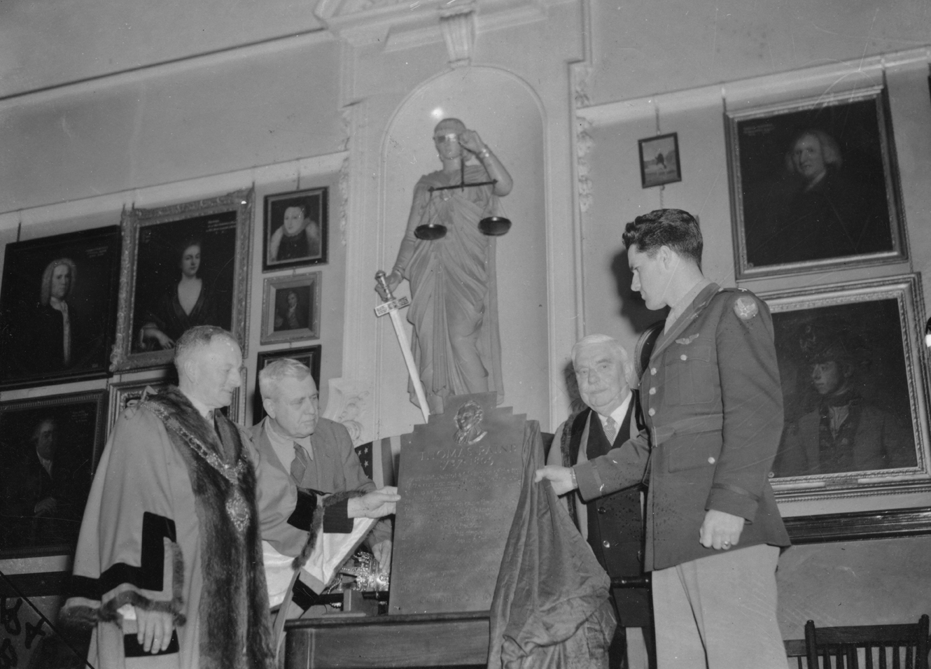 Lieutenant-Colonel Robert B Satterwhite of the 388th Bomb Group presents a plaque of behalf of the United States Eighth Air Force to the Mayor of Thetford, HR Watling, historian Professor Frank Dobie and Sir William Gentle to commemorate Thomas Paine. Image stamped on reverse: 'Associated Press.' [stamp], 'Passed for publication 25 Oct 1943.' [stamp] and '289762.' [Censor no.] Printed caption on reverse: Printed caption on reverse: 'AMERICAN SERVICEMEN'S TRIBUTE TO TOM PAINE. A Plaque in memory of Thomas 