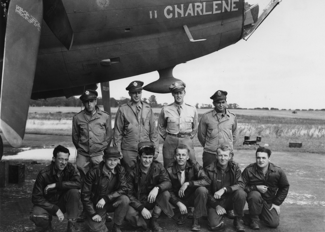 A bomber crew of the 388th Bomb Group with their B-17 Flying Fortress (serial number 42-30177) nicknamed "Charlene". Printed caption on reverse: '61552 AC- Crew of the 562nd Bomb Squadron, 388th Bomb Group, beside the Boeing B-17 Flying Fortress "Charlene". England. 30 August 1943. Standing left to right are: 2nd Lt John N Harlan, Boise, Idaho; 1st Lt Charles Bliss, Los Angeles, California; 2nd Lt Vernon D Dunkin, Columbus, Ohio; 2nd Lt Bernard J Quenneville, Hadley, Mass. Kneeling left to right: S/Sgt Ro