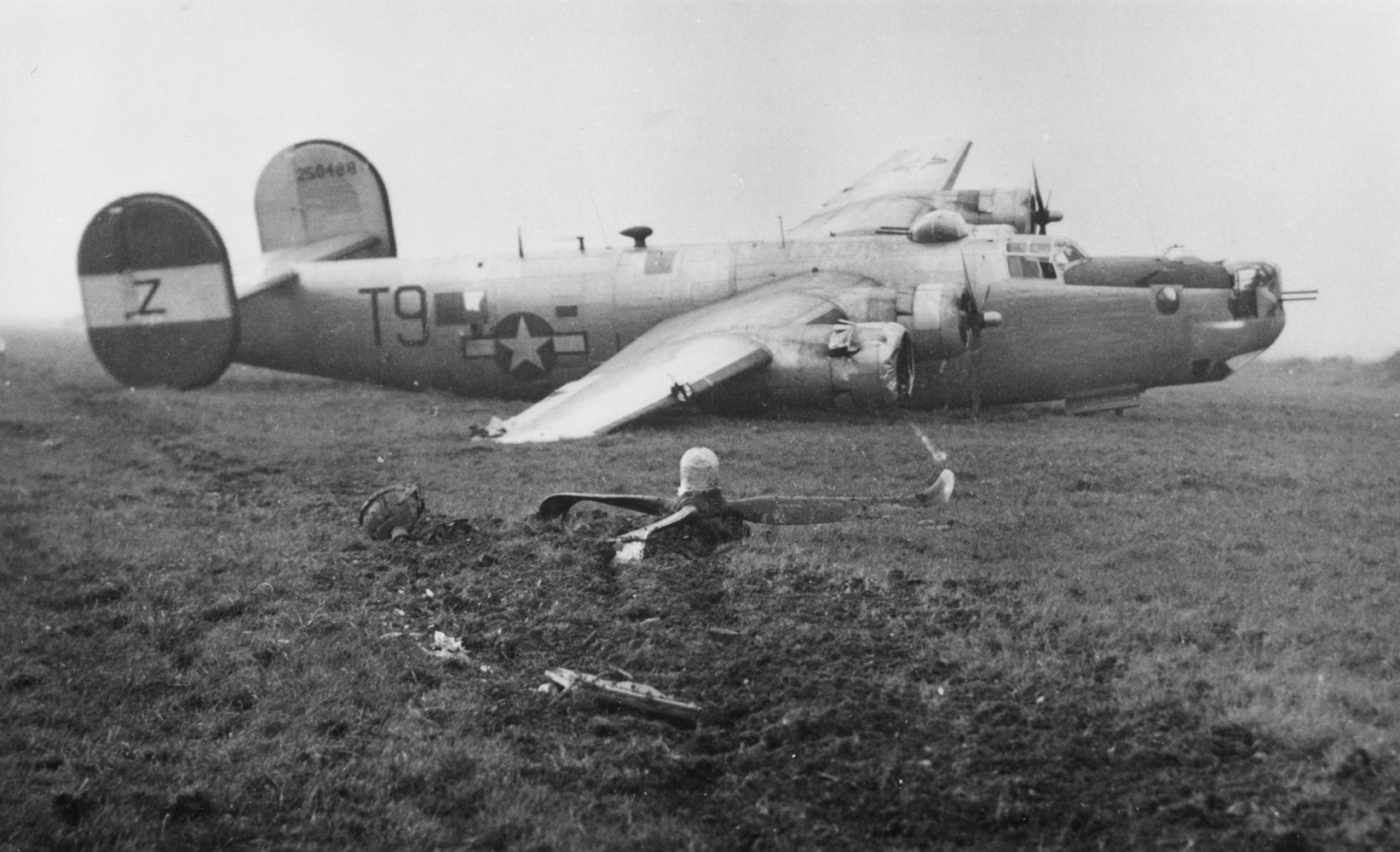 A crashed B-24 Liberator (T9-Z, serial number 42-50488) nicknamed "Polaris II" of the 466th Bomb Group. The propellor of the aircraft lies a short distance away from the wing. First handwritten caption on reverse: '2/1/45 B-24 250488, 466.' Second handwritten caption on reverse: '466 BG Attlebridge, Norfolk PFF A/C repaired and used by 785 BS on 189 mission 25/2/45.'