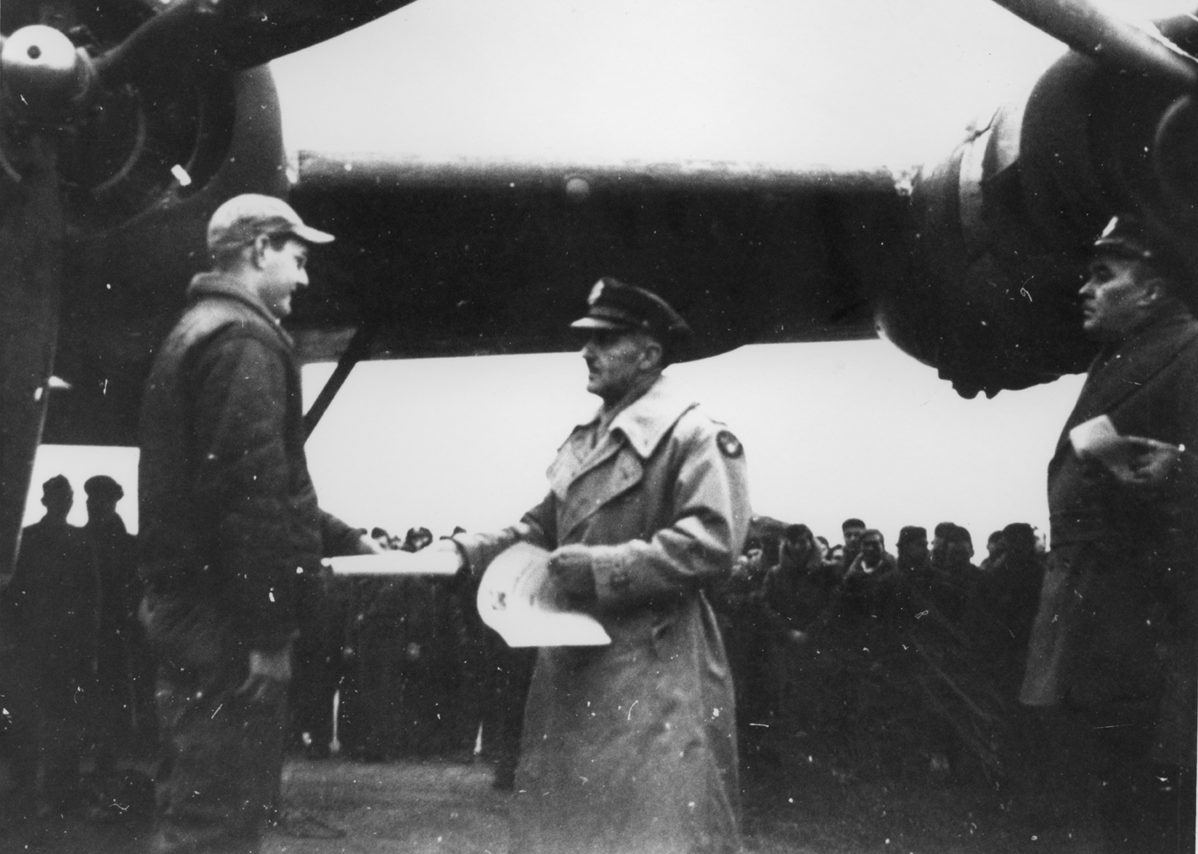 An airman of the 467th Bomb Group is congratulated by a senior USAAF officer standing by a B-24 Liberator.