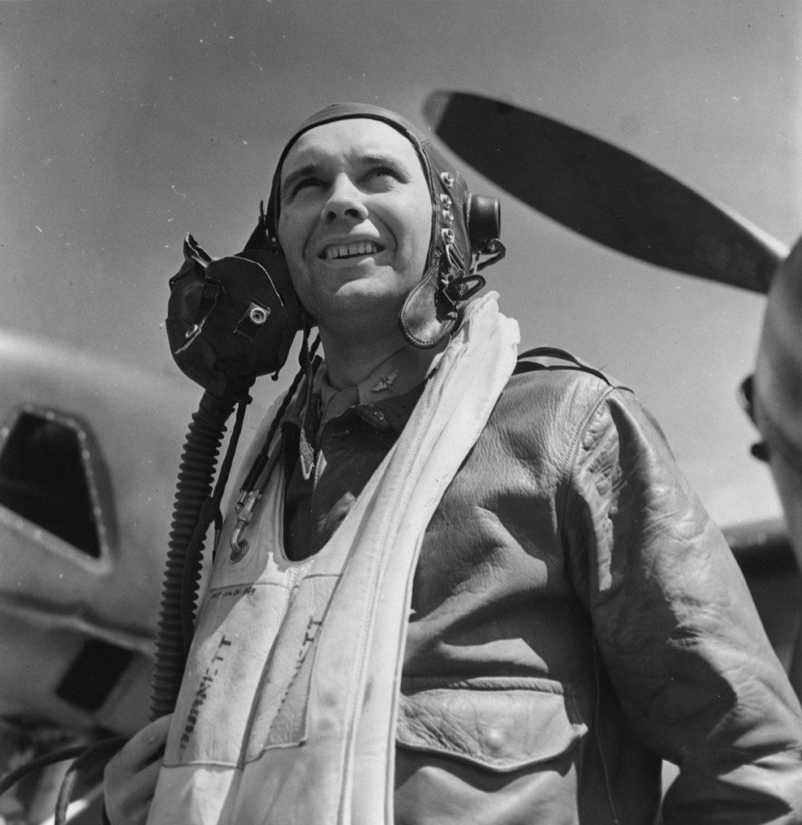 Captain JS Wright of the 7th Photographic Reconnaissance Group with an F-5 Lightning. Image stamped on reverse: 'Esten Illustrated.' [stamp], 'Passed for Publication 8 Jul 1943.' [stamp] and '273519.' [Censor no.]. Printed caption on reverse: 'Esten (Illus). Modern "Cyclops" of the USAAF. OPS 19: Capt JS Wright. 8.7.43'