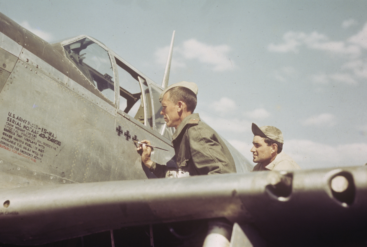  An airman of the 325th Fighter Group, 15th Air Force paints a "Kill" marker onto the fuselage of a P-51 Mustang (serial number 43-24856).