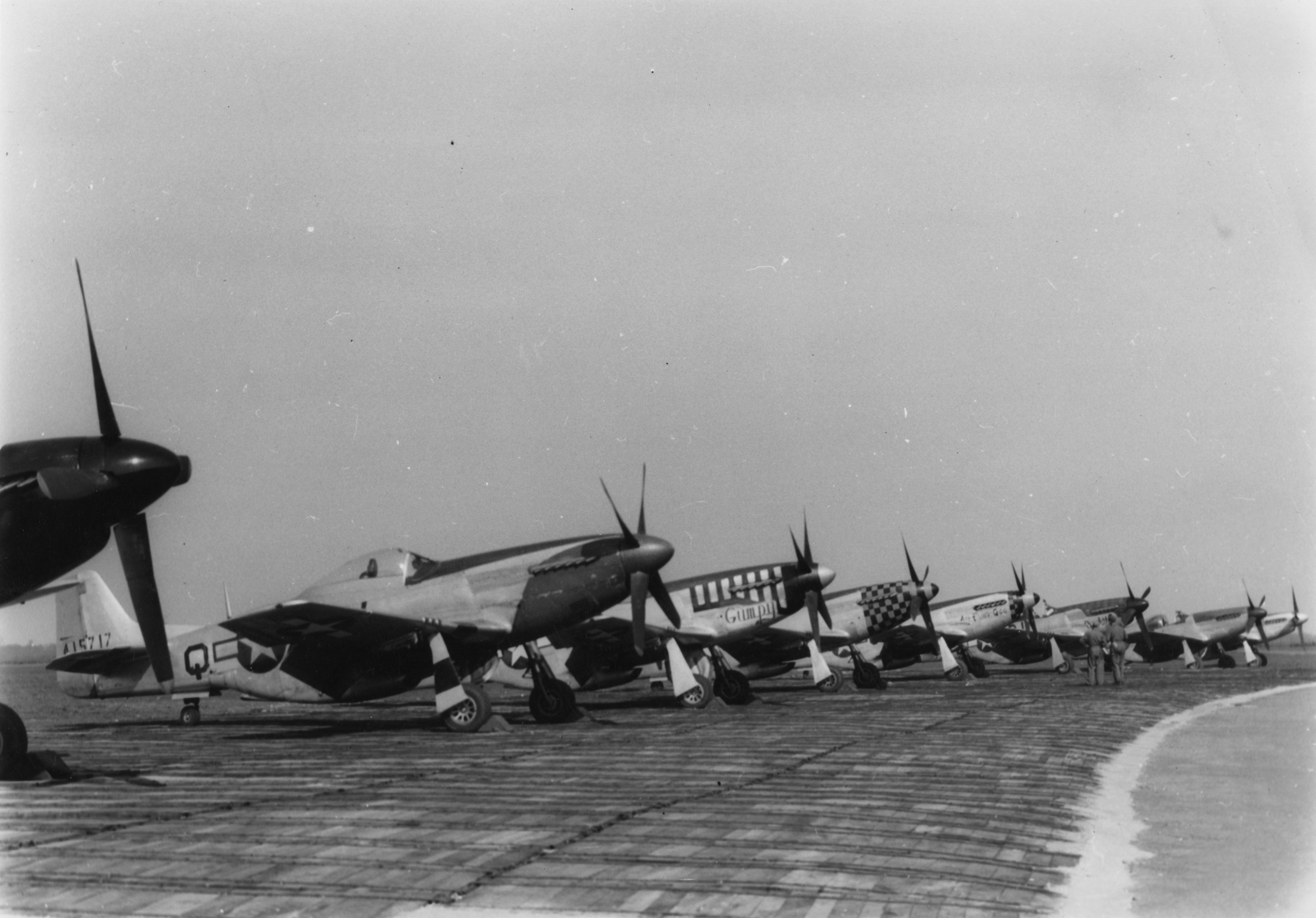 P-51 Mustangs (CV-Q) of the 359th Fighter Group, (LC-D) of the 20th Fighter Group, (LH-V) of the 353rd Fighter group and (C5-Q) of the 357th Fighter Group, at Debden, home of the 4th Fighter Group. Handwritten caption on reverse: 'Debden/ G Weckbader.'