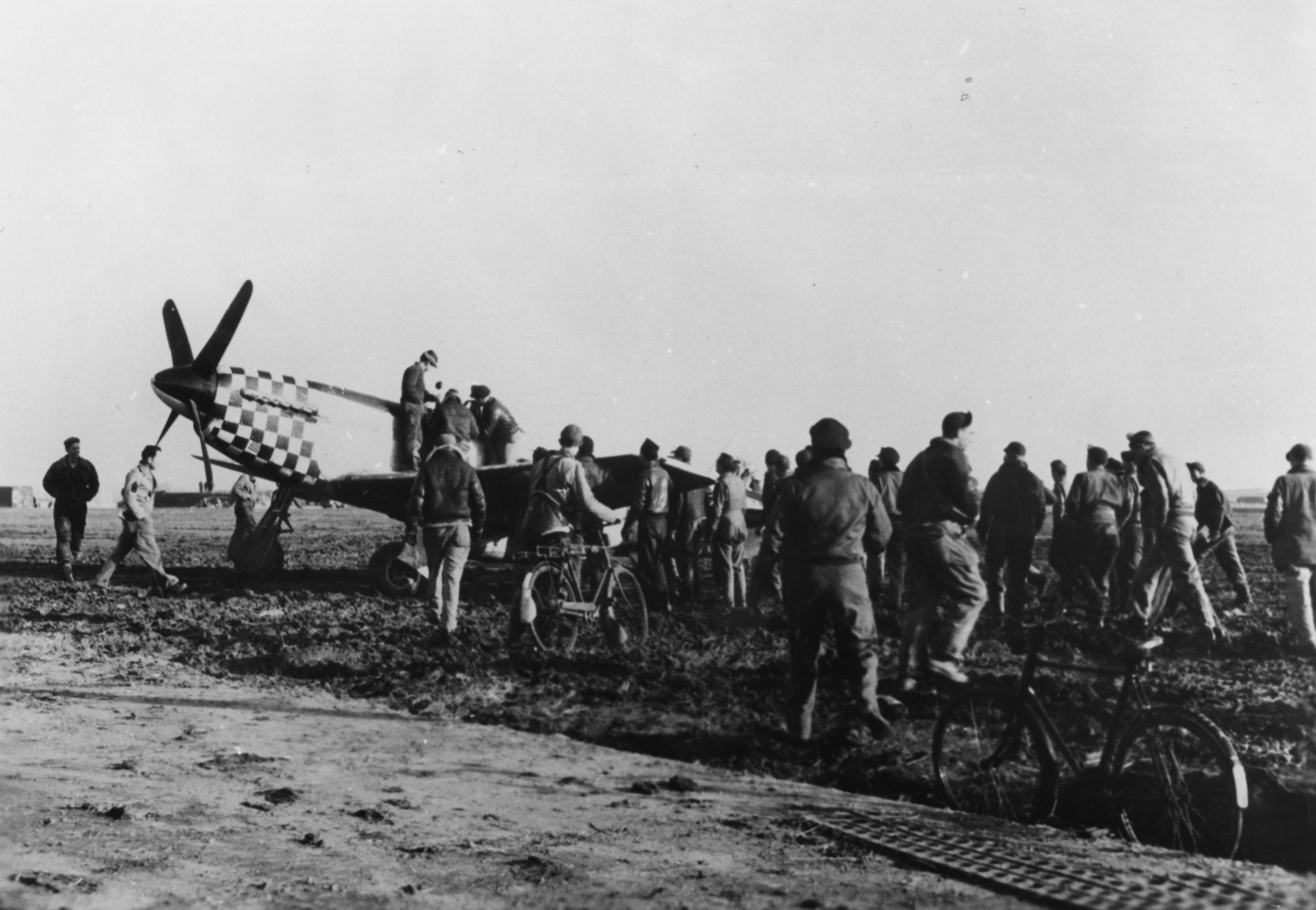 Personnel of the 78th Fighter Group gather to greet First Lieutenant Earl L. Stier after a mission in his P-51 Mustang. Handwritten caption on reverse: '1/3/45 A. 3/2/45. 1st Lt. Earl L Stier, 84FS, 78FG, Duxford, MacTaggart.'