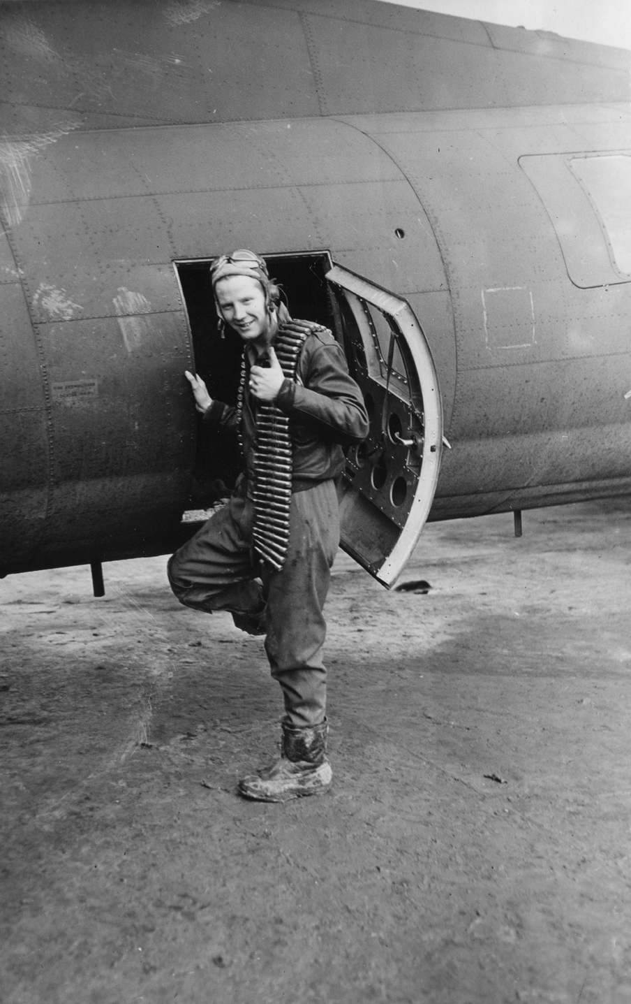 Sergeant Norman E. Olson of the 303rd Bomb Group, climbs into his B-17 Flying Fortress. Passed for publication 16 Dec 1942. Printed caption on reverse: 'Serg. Norman E. Olson, of 6110 So. Damen Avenue, Chicago, Ill. was a heat treater with the Union Special Machine Co., before the war. Now this 21 year old Chicago lad is helping to treat Hitler to a little heat - and enjoying it, judging by this picture of him climbing into his plane with a load of ammunition. His mother Mrs. Olga Olson, and his fiancee R