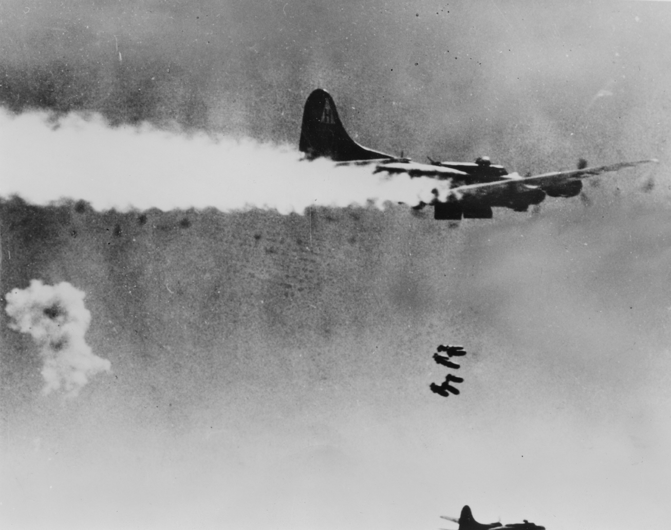 A B-17 Flying Fortress of the 306th Bomb Group trails smoke as it drops its bombs. Handwritten caption on reverse: '306BG, Berlin.'