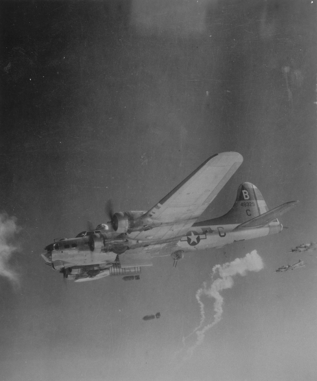 A B-17 Flying Fortress (serial number 44-8329) of the 92nd Bomb Group releases its bombs over the target. Handwritten caption on reverse: 'PY-C.'