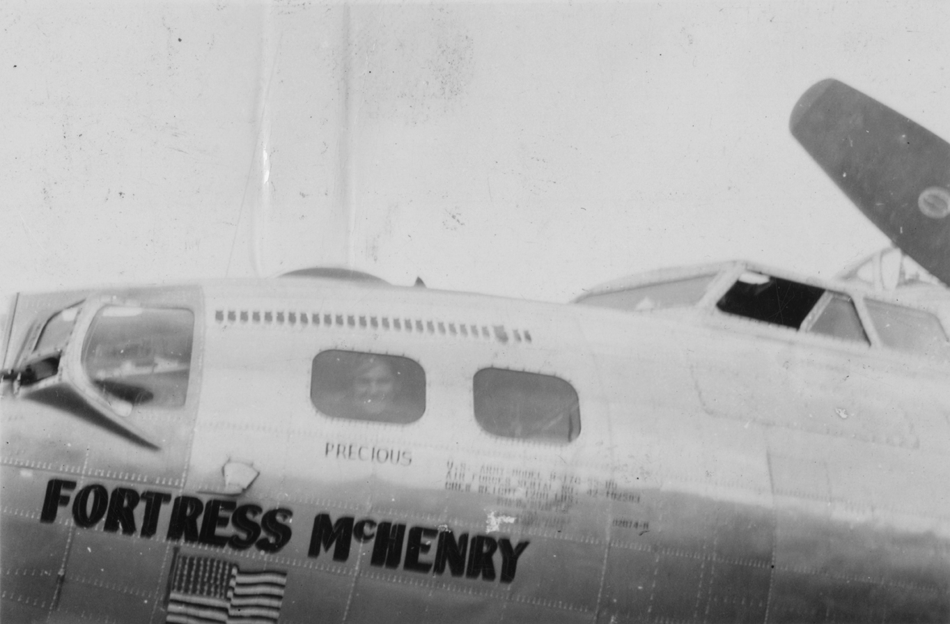 Victor Bonomo, a navigator of the 94th Bomb Group looks through the window of his B-17 Flying Fortress nicknamed "Fortress McHenry". Handwritten on reverse: 'Victor Bonomo (N) in window.'