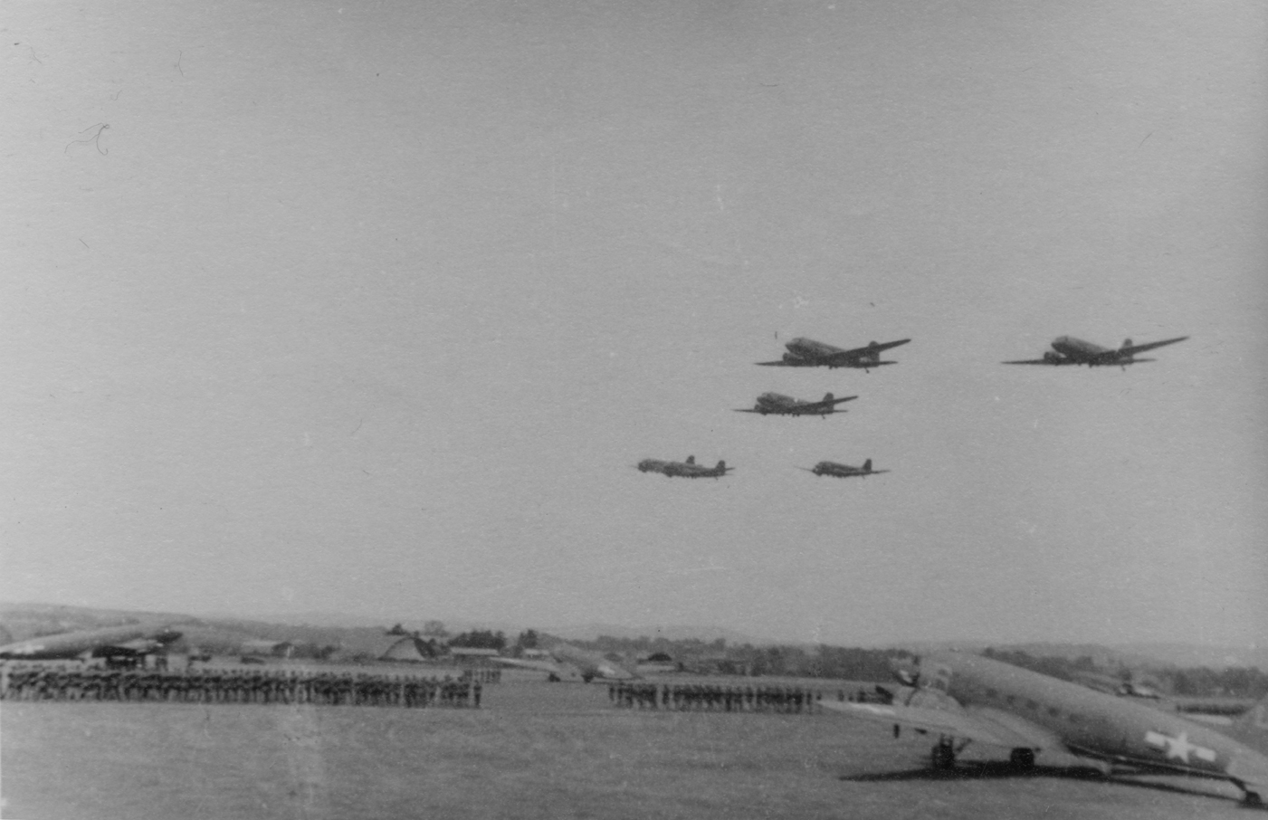 A formation of C-47 Skytrains of the 440th Troop Carrier Group fly over Exeter. Handwritten caption on reverse: 'Exeter: troops on parade.'