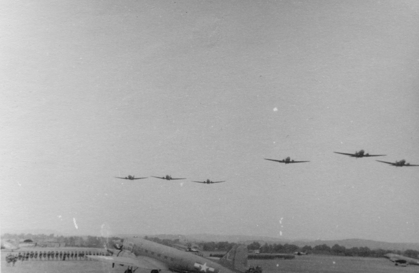 A formation of C-47 Skytrains of the 440th Troop Carrier Group fly over Exeter. Handwritten caption on reverse: 'Exeter: troops on parade.'