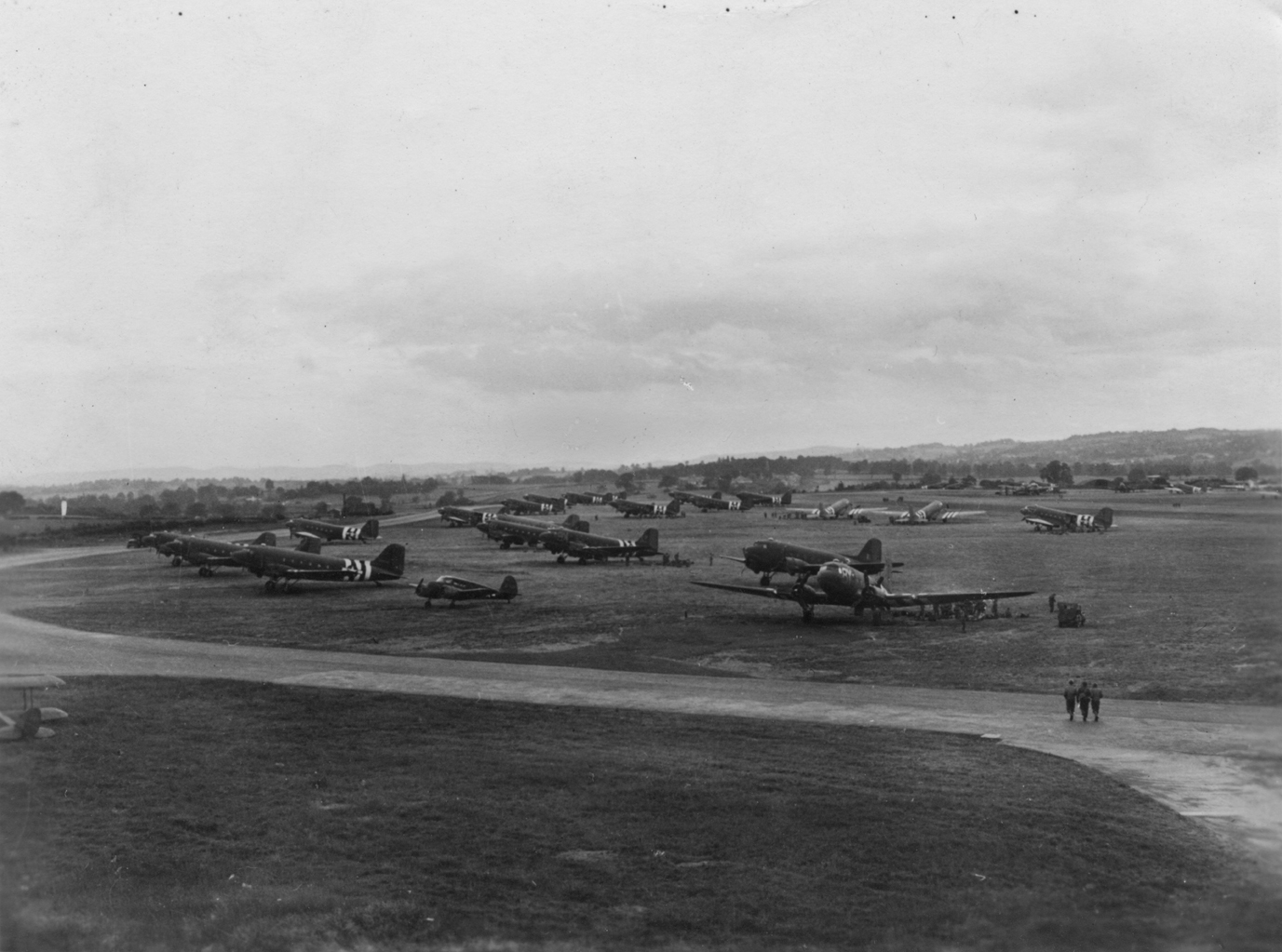 C-47 Skytrains of the 440th Troop Carrier Group at Exeter, 5 June 1944. caption on image: "Exeter, England - Jun 5, 1944, D-1." Printed caption on reverse: 'USAAF Station #463 Exeter, Devon, June 5, 1944, D-Day Minus One. Aircraft of the 95th & 98th Sqdns in foreground. Property of the 440th TCGp Assoc. 551 So. Concord St., Seattle, Washington, 98108, U.S.A.' Part of IX Troop Carrier Command.