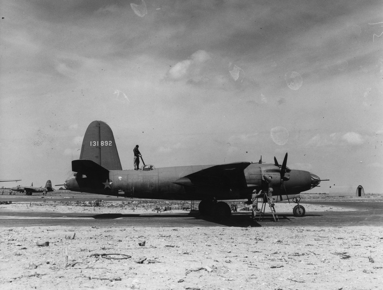 Ground personnel of the 323rd Bomb Group work on a B-26 Marauder (serial number 41-31892). Passed for publication 18 Aug 1943. Printed caption on reverse: 'America's New Super Medium Bomber In Britain. 18.8.43. The U.S. Super Medium bomber, the "Marauder" is now operating from Britain after doing fine work in N. Africa and Sicily. It has a range of 2,000 miles with a speed of 350 m.p.h. and a wing span of 65 ft., and carries one ton of bombs. Driven by two 2,000 h.p. Pratt and Whitney "Wasp" engines, arme