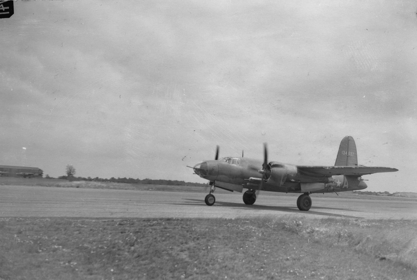 A B-26C Marauder (VT-A, serial number 41-34687) of the 453rd Bomb Squadron, 323rd Bomb Group orepares for take off. Not To Be Published 24 Jul 1943. Handwritten caption on reverse: 'Looking East toward EC - Cogeshall Road.' Printed caption on reverse: 'Fastest Medium Bomber In Use Now Operating From This Country. Associated Press Photo Shows:- Taking off at top speed, a Marauder sets out on an operational flight. WOR 259119. 24-7-43-Y.' Censor no: 276103. On reverse: Ministry of Information, Associated Pr