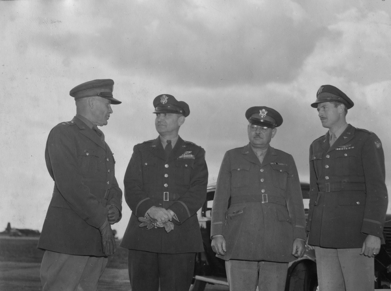 General Lee, General Ira C Eaker, and General Moore with Lieutenant-Colonel Elliot Vandevanter Jr Commanding Officer of the 385th Bomb Group during an official visit. Passed for publication 28 Sep 1943. Printed caption on reverse: 'Youth Of The Flying Fortresses. USP/224I-83. The Big Chiefs look in on the Fortress Unit of Youth - (left to right) General Lee; General Eaker; General Moore, with the station's young Commanding Officer, Lt. Col. Elliot Vandevanter Jr., aged 26, photographed during a tour of in