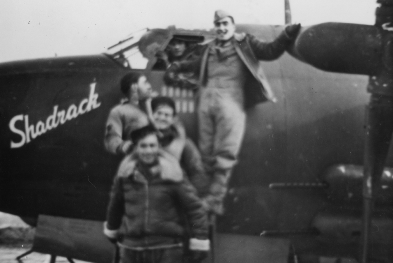 A bomber crew of the 386th Bomb Group with their B-26 Marauder (RG-U, serial number 41-31586) nicknamed "Shadrack". 

Printed caption on reverse: '552nd B.S. 386th B.G. A/C Name Shadrach, A/C Ser. No. 131586. RG-U RU-J. From front to rear: 1) R/G Howard R. Scholz, 2) A/G Aubrey L. Ruess, 3) E/G Rubin Rosen, 4) B/N Charles J. Cilfone, 5) Pilot Romney J. Spencer, 6 C/P Glenn L. Johnson. (Spencer was the pilot who ditched Margie).' 

On reverse: From Photo Files Of Chester P. Klier [Stamp].