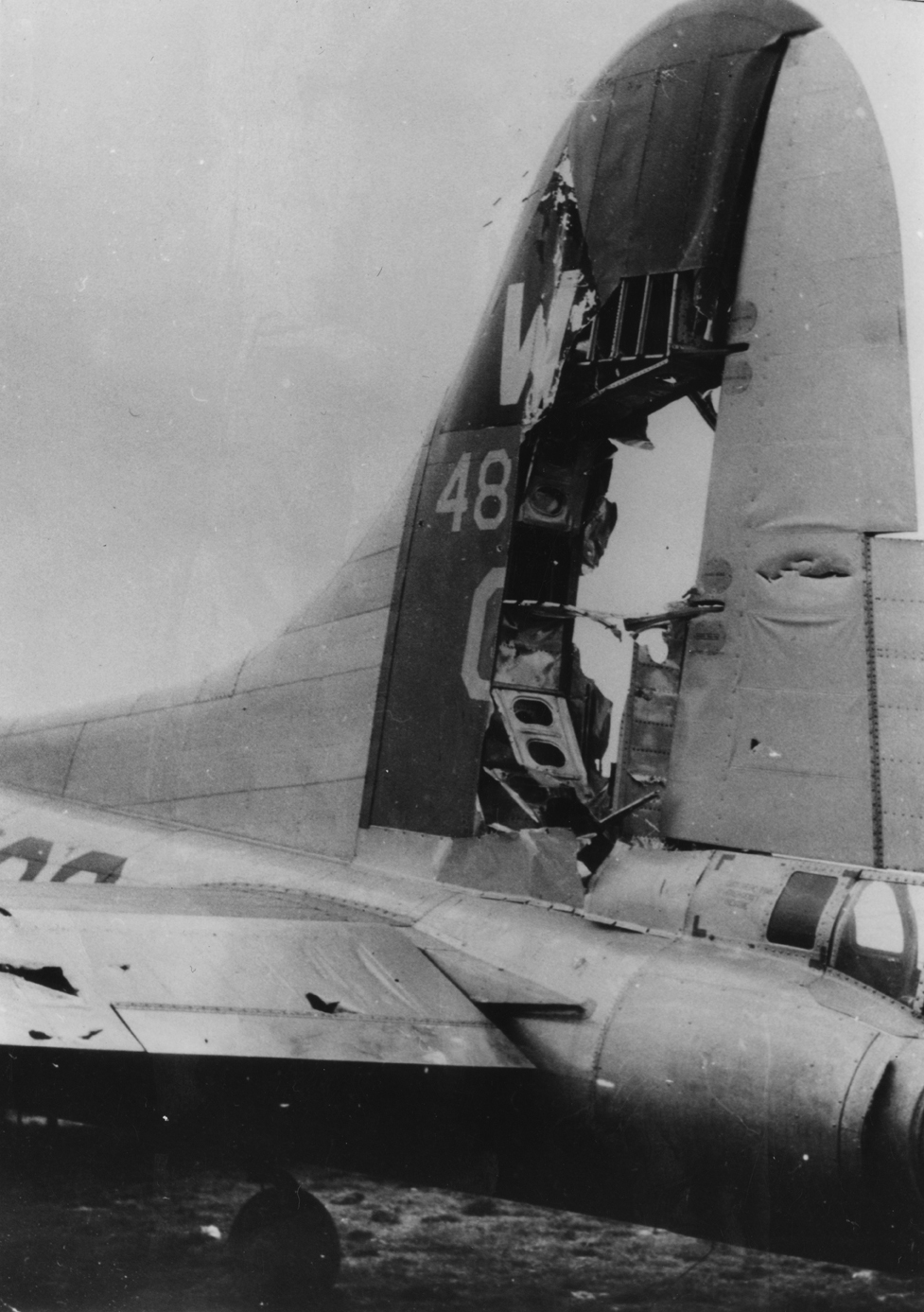 The battle damaged tail of a B-17 Flying Fortress (N8-Q, serial number 44-6899) of the 398th Bomb Group damaged by an Me 262 at Manston, 10 April 1945. Handwritten caption on reverse: '46899 N8-Q 600BS 10/4/45 Me262 damage - no casualties. Manston a/f. Lt. Shaffer. 398BG. USAAF 60. Credit Archer.'