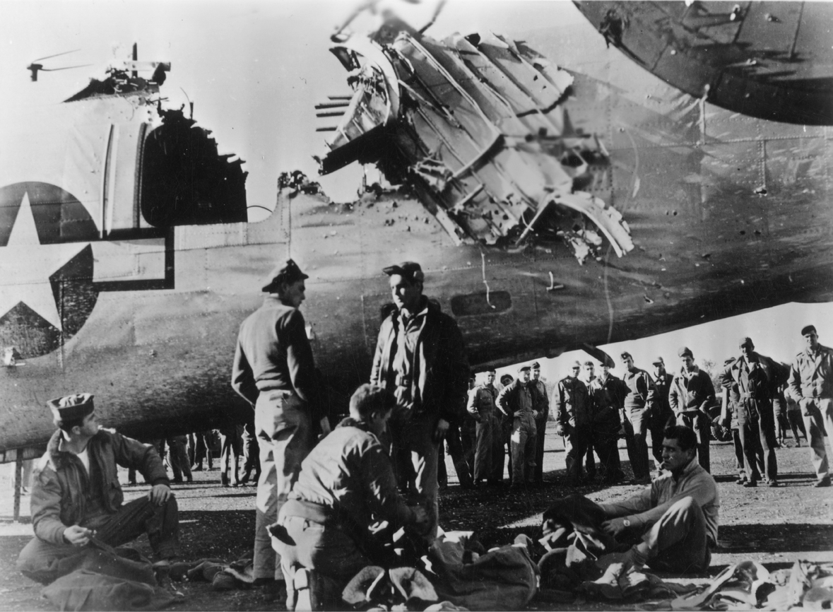 Personnel of the 15th Air Force with their flak damaged B-24 Liberator. Official caption on image: 'Controls severed by flak burst, B-24 came in on engines only US Air Force Photo.'