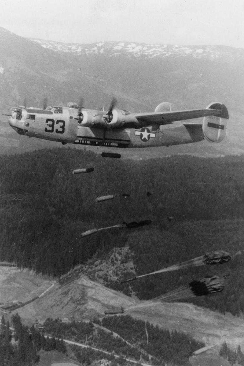 A B-24 Liberator of the 461st Bomb Group, 15th Air Force drops supplies over a Prisoner of War camp in Austria, May 1945. Handwritten caption on reverse: '9 May 1945, Last 'combat' mission of 461st BG to British POW camp near Villack, Austria. #33 flown by Lt John Stegman- 765th BS.'