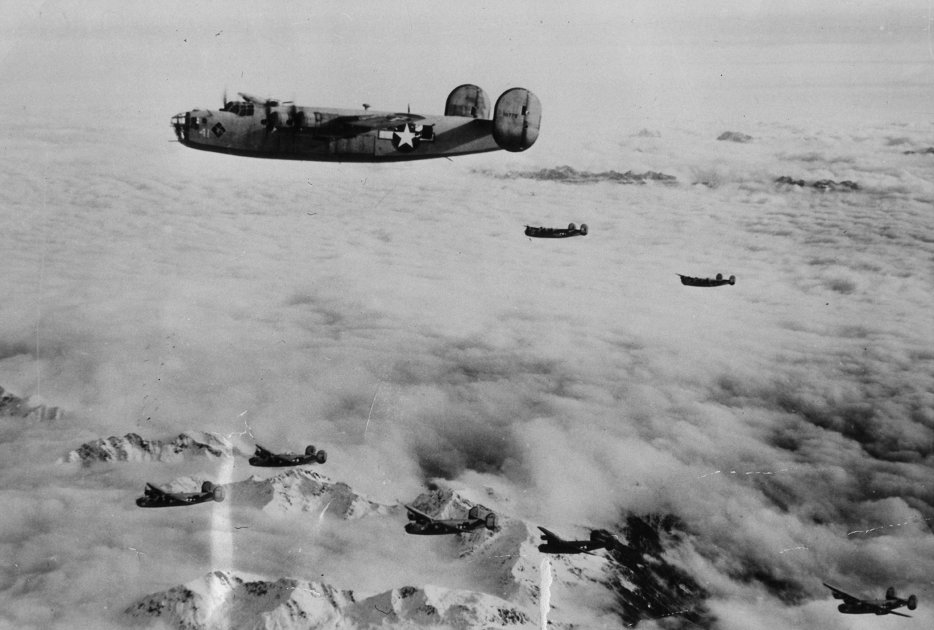 B-24 Liberators of the 99th Bomb Group, 15th Air Force fly in formation over the Alps. Printed caption on reverse: 'AFHQ Dec.29th - American bombers headed for Germany. Flying over the Alps are these long range bombers, B-24 Liberators, of the 15th USAAF, on a mission to smash vital centers in the Axis lines of communications. USAAF photo thru PWB. Serviced by Algiers to B List, NA and IT. Approved by appropriate military authority. Reserviced by OWI London to List G.'