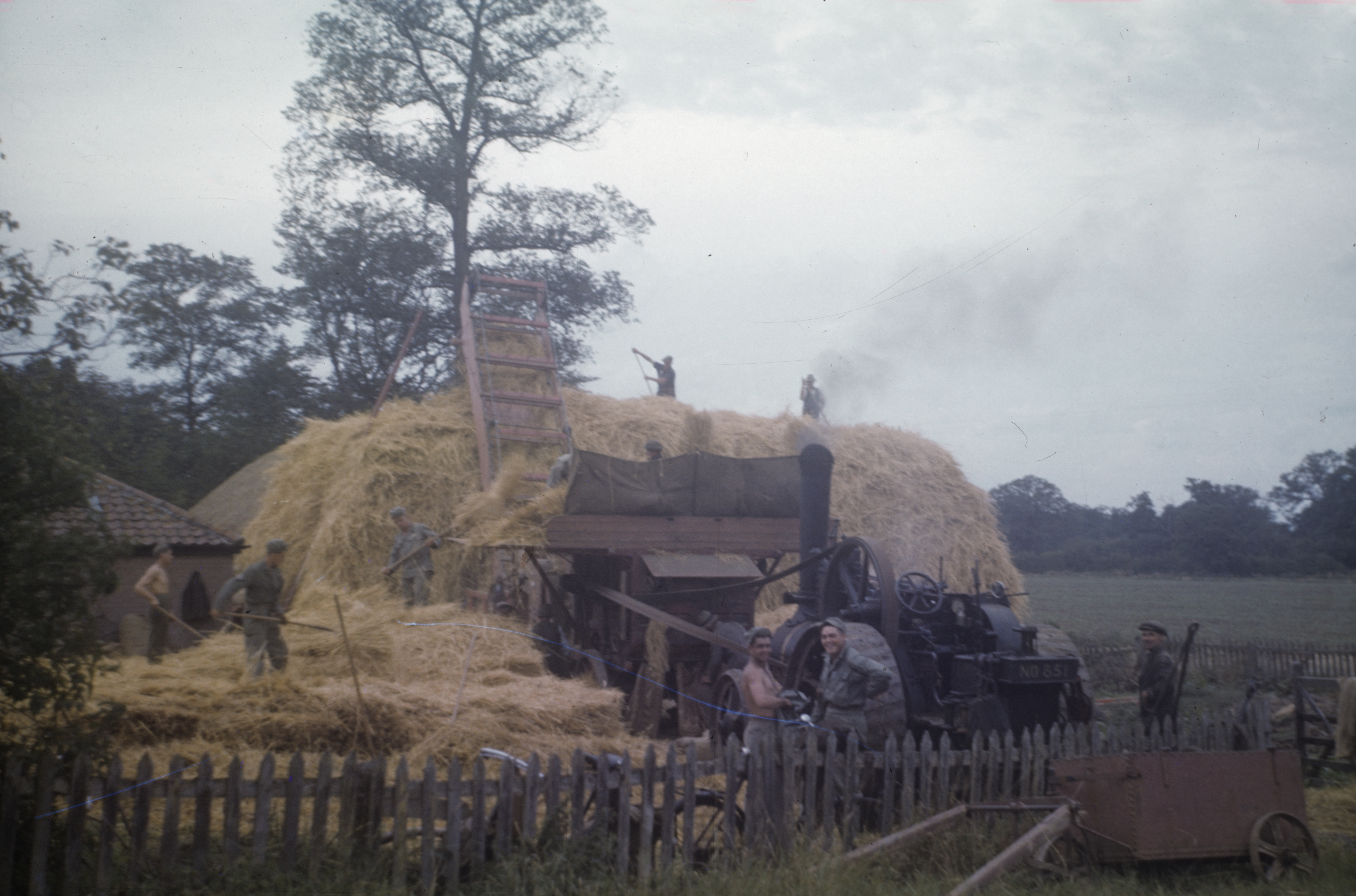 Personnel of the 466th Bomb Group assist a farmer at Bungay, 1944. Image via George Parker. Written on slide casing : 'Bungay 1944.'