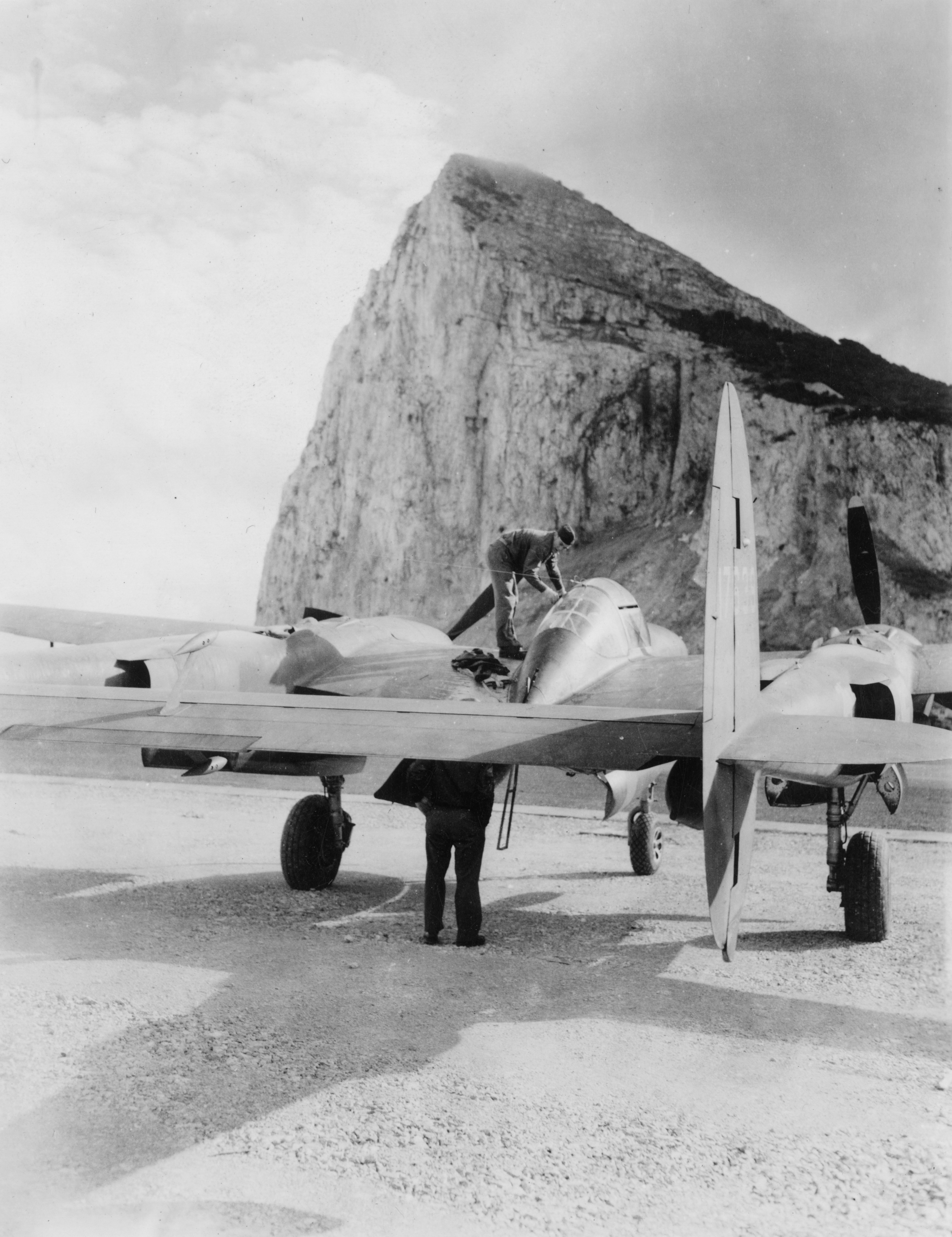 Airmen of the 14th Fighter Group, 12th Air Force work on a P-38 Lightning in Gibraltar. Image stamped on reverse: 'Not to be published 26 Nov 1942'[stamp], '235287.'[censor no.] Printed caption on reverse: 'AFNA-ZEI-42-1745, Nov 10 42. US fighter plane on air-drome somewhere in Mediterranian theater of war'