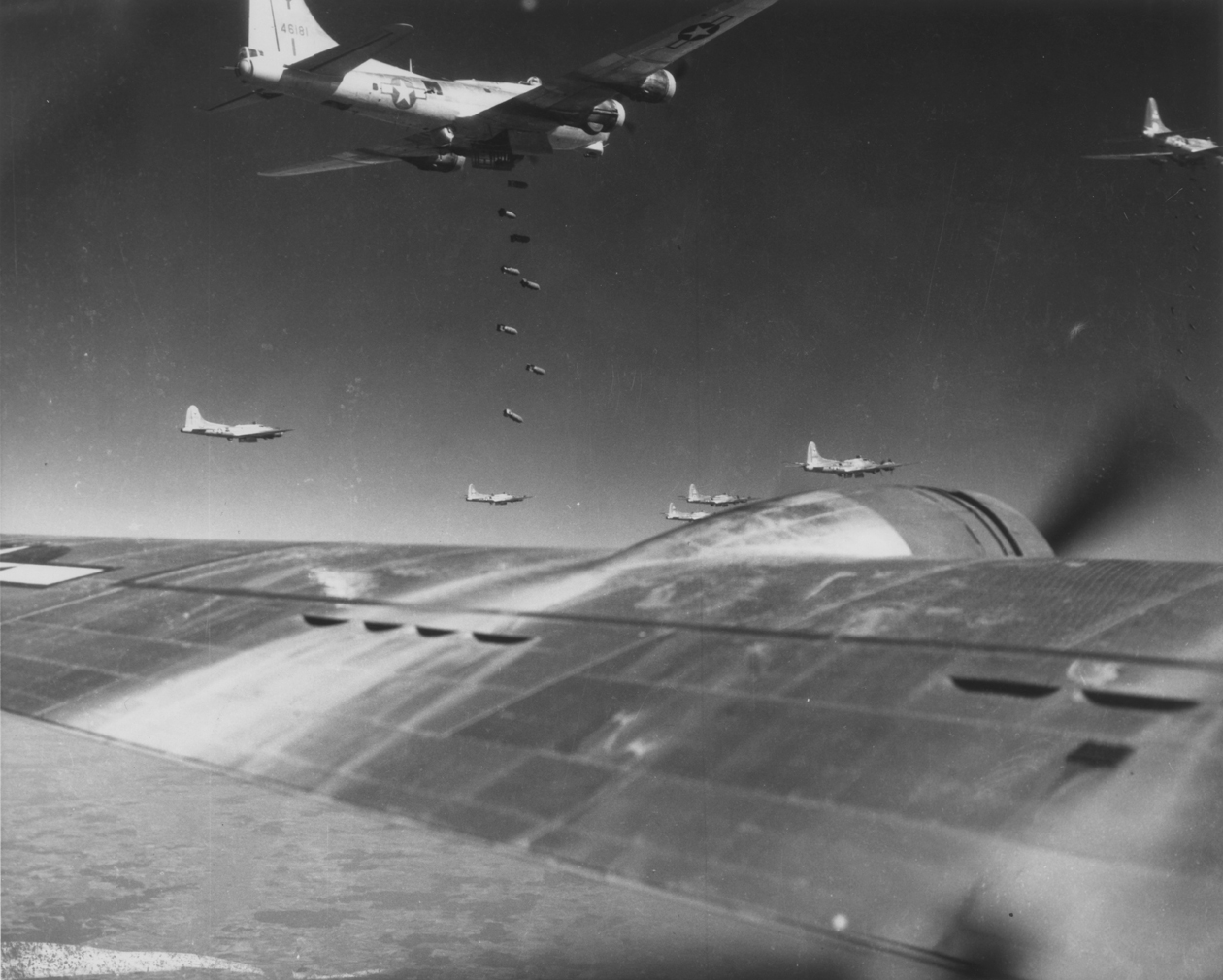 97th Bomb Group B-17 Flying Fortresses, including (serial number 44-6181), drop their payloads on Lechfeld airdrome on the 12th of September 1944. Printed caption on reverse: '62004 AC - Bombs Away - Boeing B-17 Flying Fortresses of the 15th Air Force release their string of bombs on the airdrome at Lechfeld, Germany, 12 Sept. 1944. U.S. Air Force Photo.' On reverse: Substandard Original Material and US Air Force 1361st Photographic Squadron AAVS (MAC) Photo [Stamps].