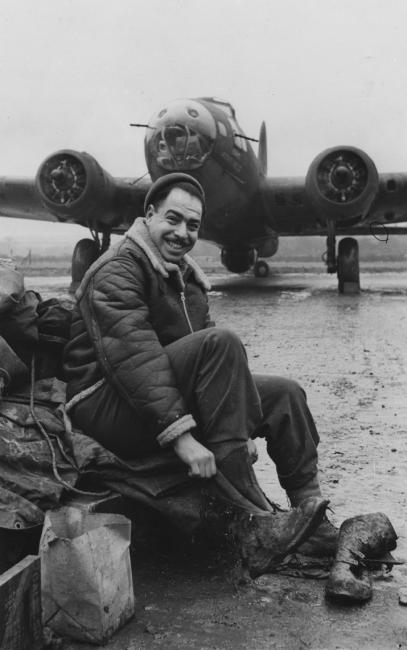 Corporal Murray S. Pearl, of the 303rd Bomb Group, with a B-17 Flying Fortress (serial number 41-24565) nicknamed "Idaho Potato Peeler". Image stamped on reverse: ‘Copyright Current Affairs Ltd.’ [stamp], ‘Passed for Publication 28 Jan 1943. [stamp] and ‘245656.’ [Censor no.] Printed caption on reverse: 'Cpl. Murray S. Pearl, serving with the U.S.A.A.F in a bomber squadron, appreciates the heavy fur-lined jerkin issued to him, for, in private life, he was a fur manufacturer at 222 West 28th Stre